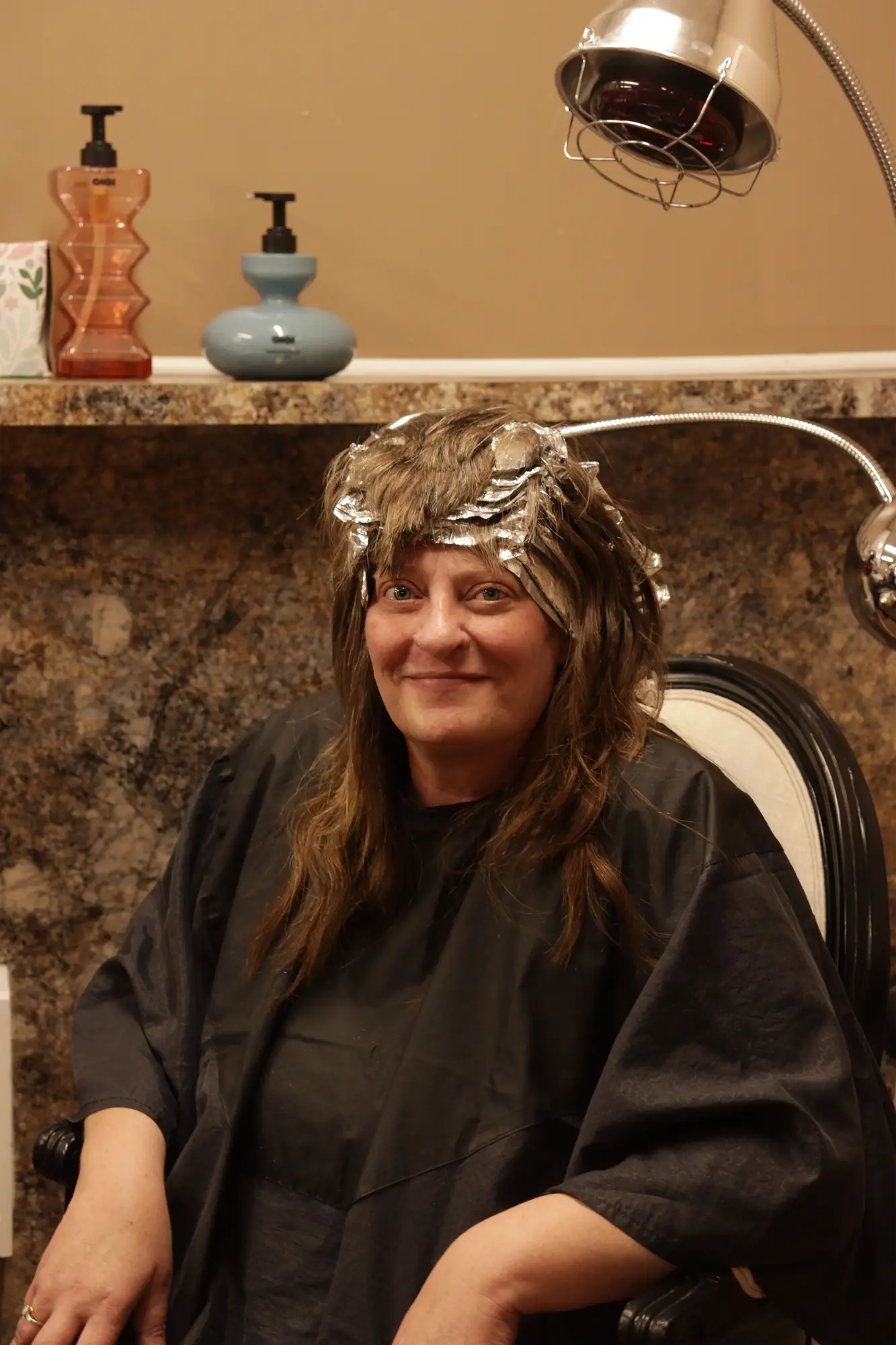 A client beneath the salon dryer at The Scissor Joint