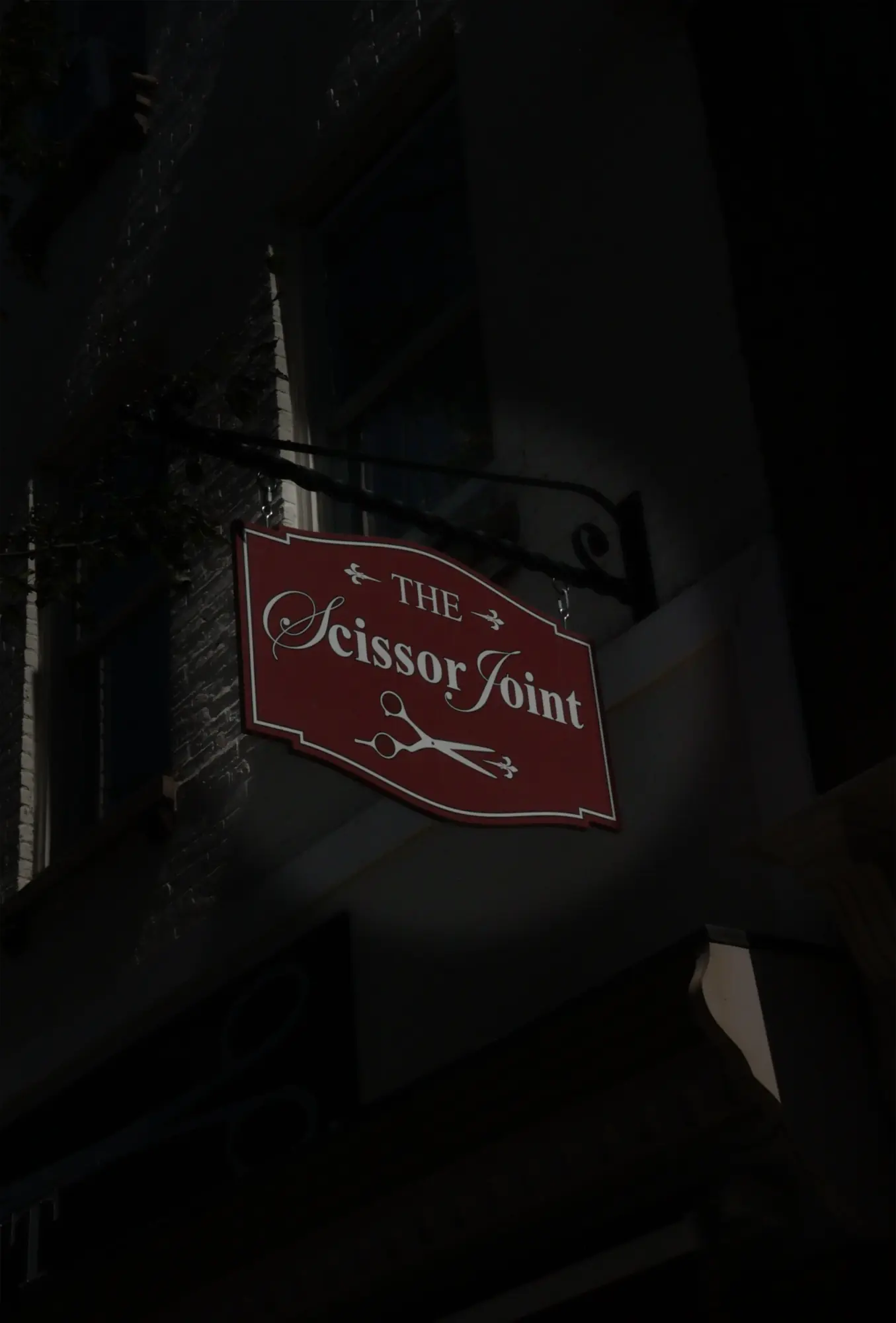 The Scissor Joint hanging sign after dark