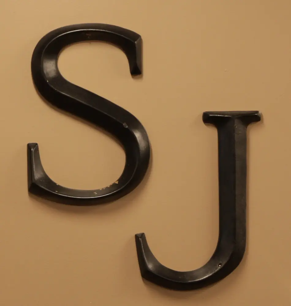 The Scissor Joint SJ logo on a warm gold background